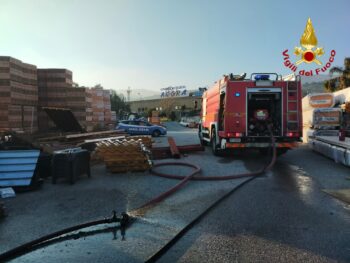 In fiamme materiale vario in piazzale interno di una attività commerciale, grossa colonna di fumo